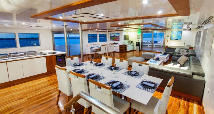 Bright dining and lounge area inside a yacht set for a formal meal with ocean views
