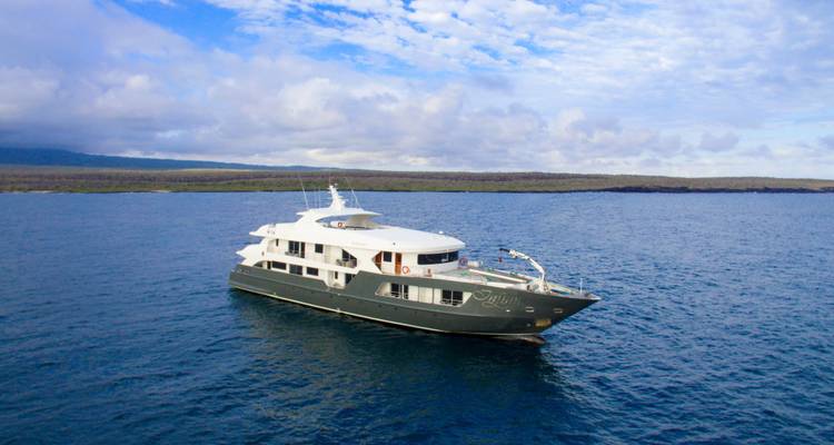 Aerial view of a luxury yacht sailing on open blue waters under partly cloudy sky