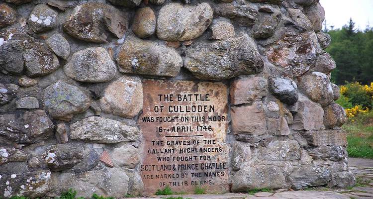 Marcador conmemorativo de piedra que recuerda la Batalla de Culloden, incrustado en un montículo de piedras rocosas.