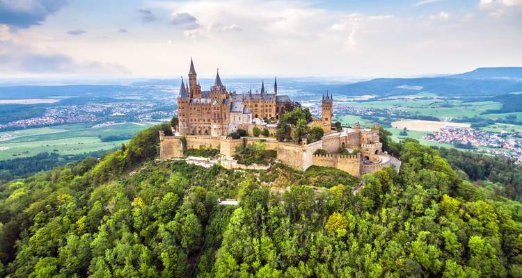 Majestic hill-top Hohenzollern Castle surrounded by dense green forest with sweeping countryside views.
