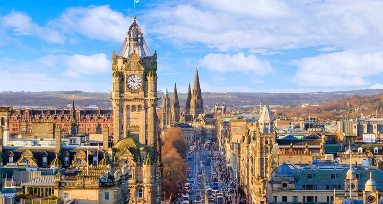 Edinburgh’s Balmoral Clock Tower and spires overlook bustling Princes Street on a bright day.