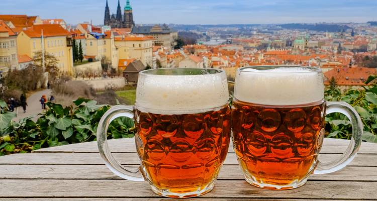 Pair of Czech beer mugs on a table overlooking the rooftops and castle of Prague.