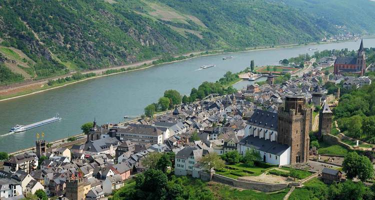 Panoramic view of Sankt Goar’s riverside village and surrounding Rhine Valley hills with passing riverboats.