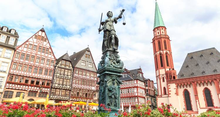 Frankfurt’s Römerberg square with the Fountain of Justice statue in front of half-timbered houses and church tower.