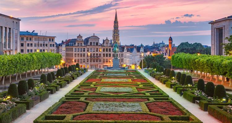 Jardins du Mont des Arts à Bruxelles avec des parterres de fleurs géométriques au coucher de soleil coloré.