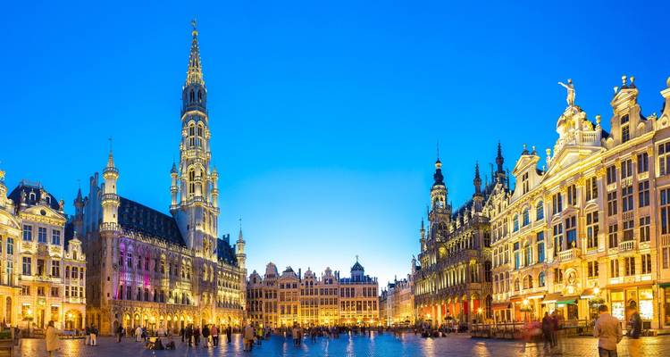 Vue panoramique du crépuscule de la Grand Place de Bruxelles avec les tours illuminées et les maisons des corporations.