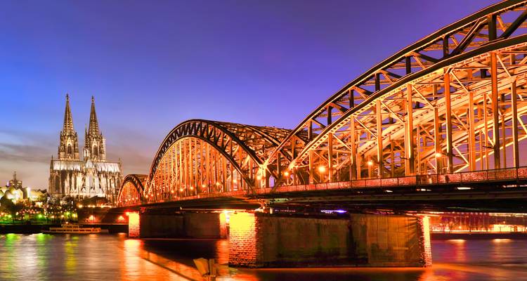Twilight over Cologne’s Hohenzollern Bridge with the cathedral spires illuminated beside the Rhine.