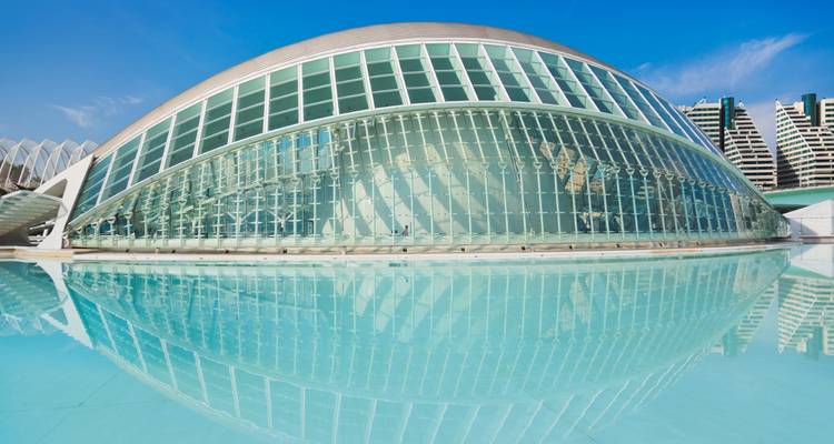 Futuristic L'Hemisfèric building in Valencia perfectly mirrored in turquoise pool under clear sky