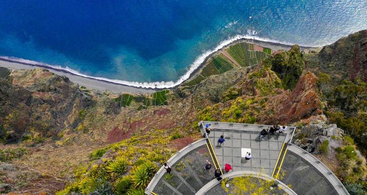 Aerial view of glass-floored Cabo Girão skywalk jutting over sheer cliffs above deep-blue ocean.