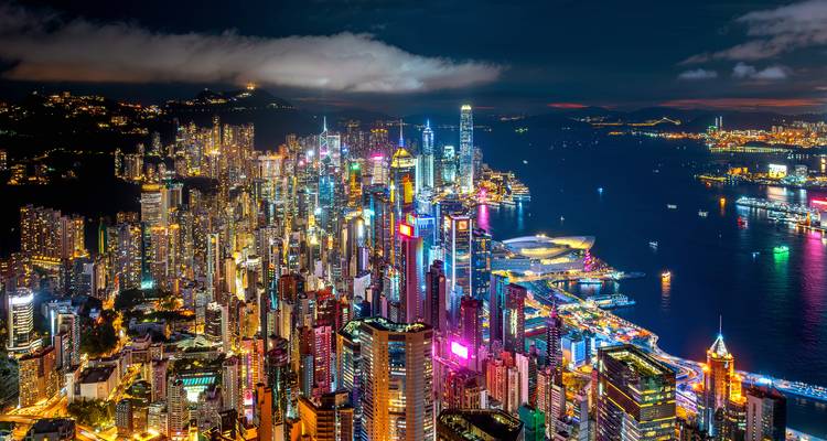 Spektakuläre nächtliche Luftaufnahme der beleuchteten Wolkenkratzer auf Hong Kong Island und des Victoria Harbour.