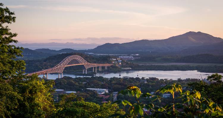 Iconische Bridge of the Americas die de jungle-omzoomde Panamakanaal bij zonsondergang overspant.