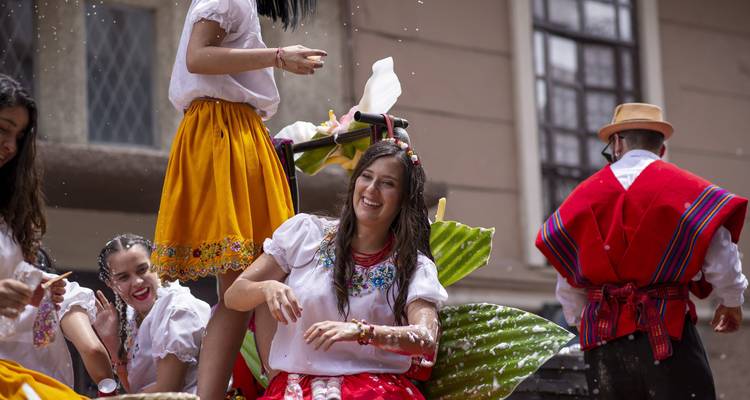 Jonge vrouwen in traditionele kleding die lachen en water spetteren tijdens een levendige straatfeest.
