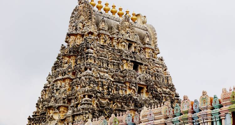 Hochdetaillierter Gopuram eines südindischen Tempels, verziert mit vergoldeten Finialspitzen.