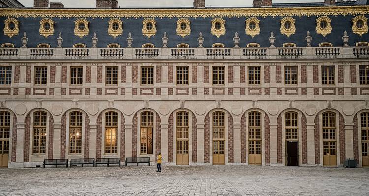 Symmetrische Fassade des Schlosses von Versailles mit einem einzelnen Besucher im Innenhof