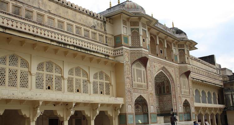 zijgevel van het Amber Fort met toeristen die onder de getraliede ramen voorbijlopen