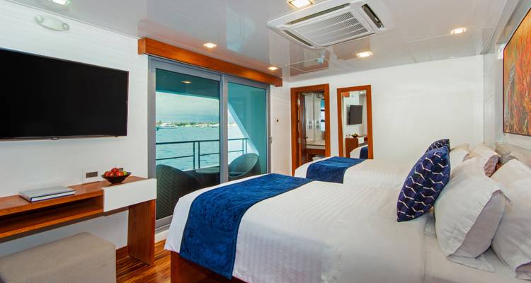 Bright modern twin cabin on a yacht with large window doors opening to sea view.