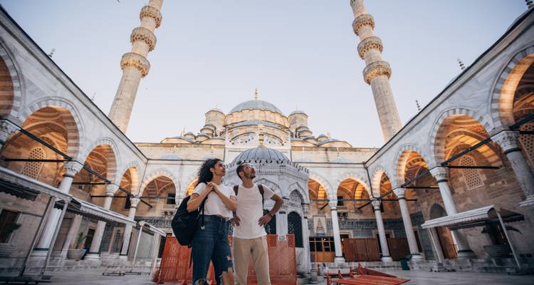Young couple admiring the ornate courtyard of Istanbul’s Blue Mosque at dusk.