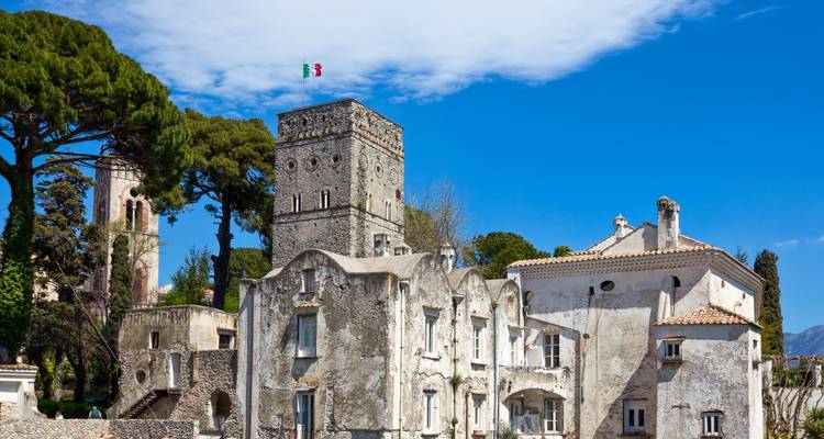 Villas en pierre historiques et tour entourées de grands pins à Ravello par une journée ensoleillée.