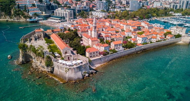 Drone view of Budva Old Town fortress jutting into turquoise Adriatic waters