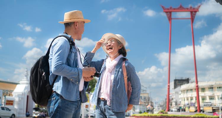 Gelukkig seniorkoppel dat naast Bangkoks torenhoge rode Giant Swing aan het praten is