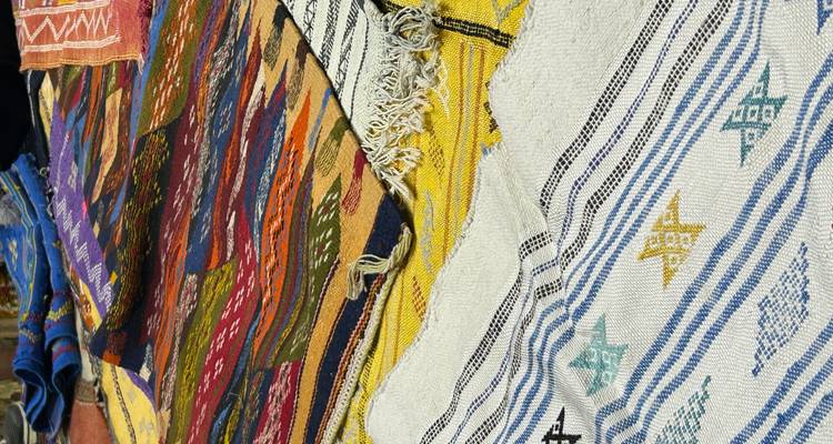 Gros plan de tapis marocains tissés aux couleurs vives exposés sur un étal du marché.