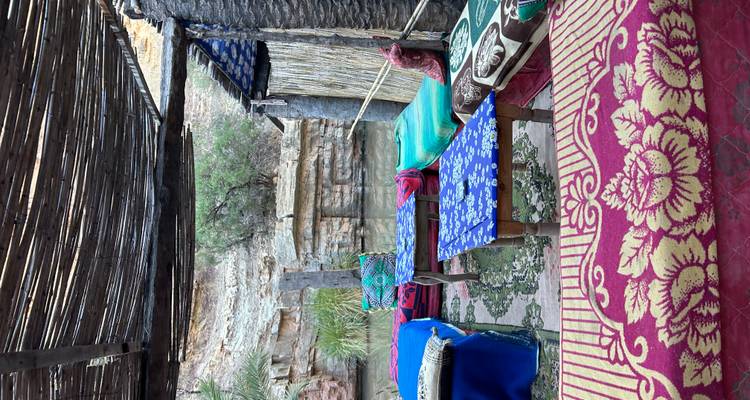 Sièges extérieurs rustiques avec des coussins colorés à côté d'une petite gorge fluviale.