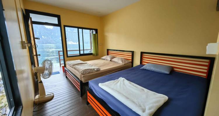Deux lits simples dans un petit chalet au bord du lac avec ventilateur et accès au balcon.
