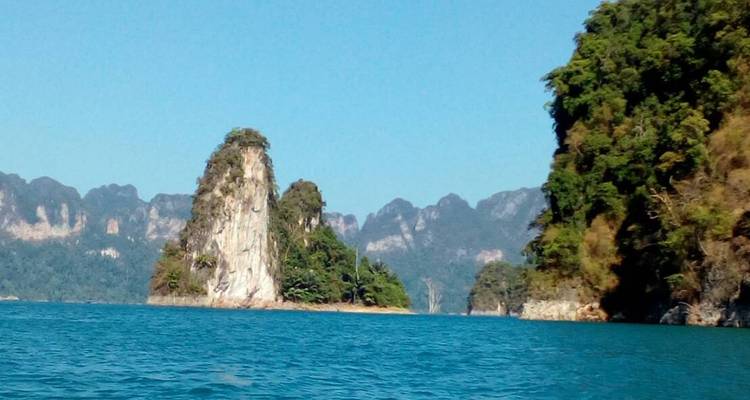 Île calcaire karstique solitaire entourée par un lac bleu éclatant sur fond de ciel dégagé.