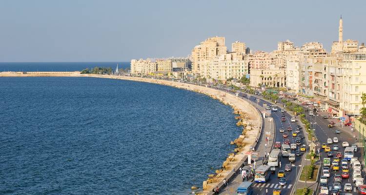 Panoramische Küstenpromenade von Alexandria mit belebter Straße und Gebäuden, die sich entlang des Meeres erstrecken.