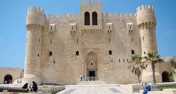 Steinerne Festung von Qaitbay mit zylindrischen Türmen vor blauem Himmel.