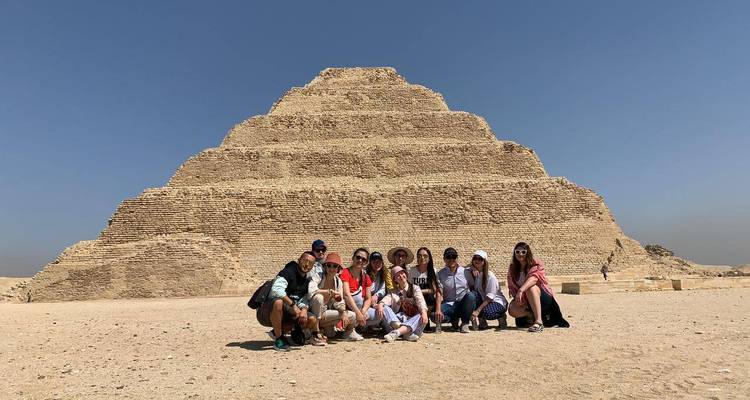 Tour group crouching together in front of the Step Pyramid of Saqqara.