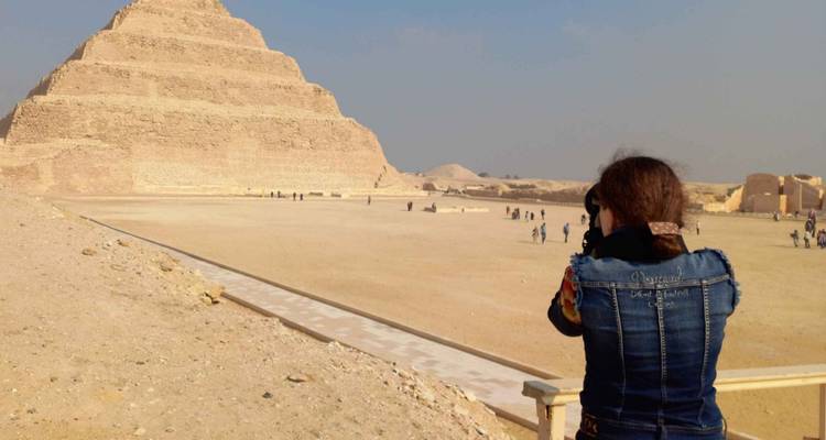 Visitor photographing the Step Pyramid from a distance on a hazy afternoon.