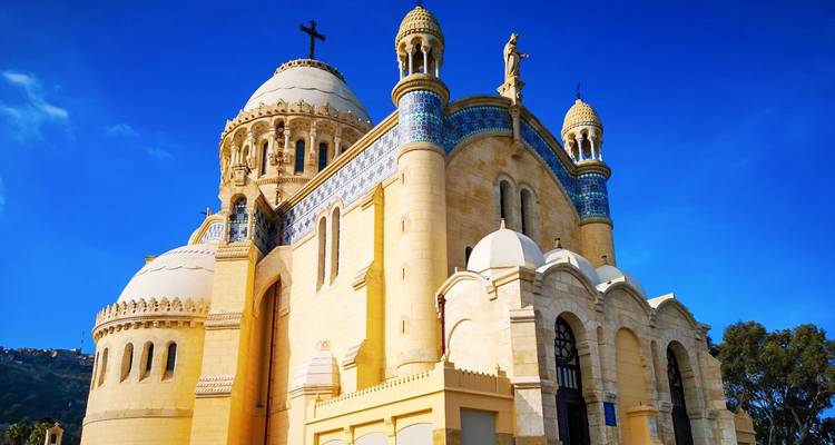 Magnificent Notre-Dame d’Afrique basilica with domes and mosaics gleaming against deep blue sky