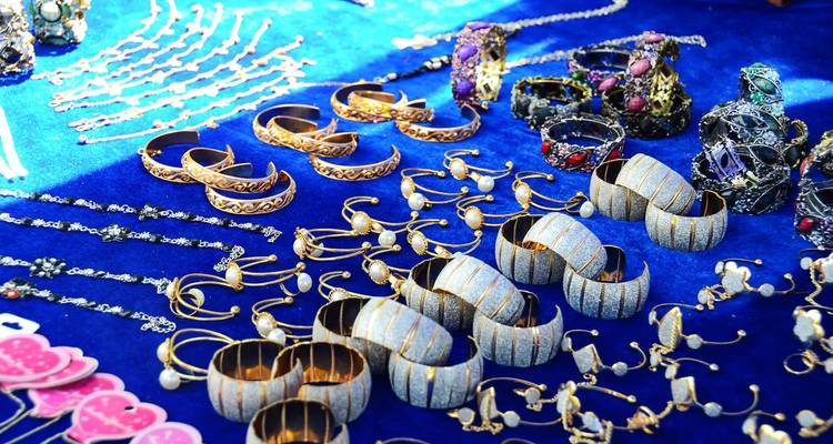 Display of ornate gold and gemstone jewellery pieces laid out on vibrant blue cloth