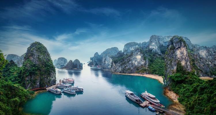 Panoramic vista of Halong Bay with emerald waters, towering karst islands and moored boats
