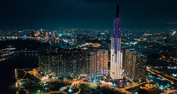 Night aerial of Ho Chi Minh City with Landmark 81 tower lit in purple above a sea of city lights