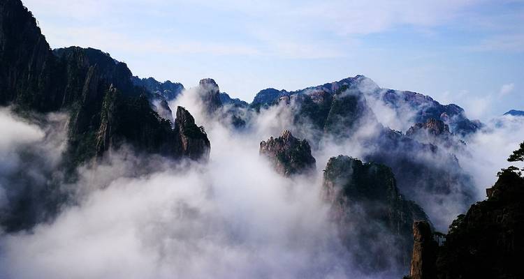 Les pics émergeant des nuages épais et ondulants au crépuscule dans la chaîne mystique de Huangshan.