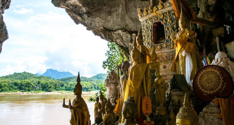 Intérieur de la grotte de Pak Ou remplie de petites statues de Bouddha surplombant le Mékong et les montagnes verdoyantes