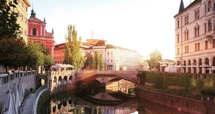 Historische Europese brug over een rustig kanaal met pastelkleurige gebouwen die gloeien in warm licht en hun spiegelingen in het water.