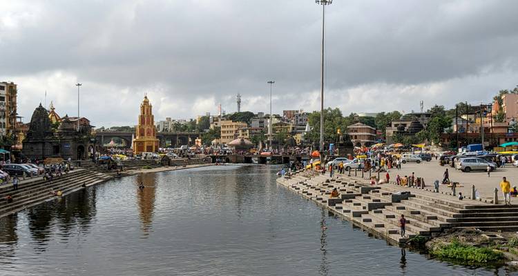 Drukke ghats en tempels liggen langs de oevers van de Godavari River in Nashik onder een bewolkte hemel