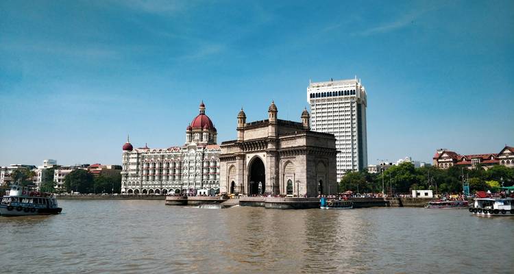 Gateway of India en het Taj Mahal Palace Hotel steken uit boven de haven van Mumbai op een zonnige dag