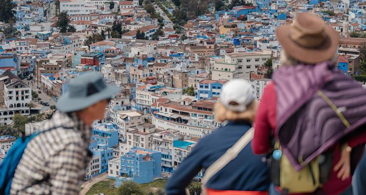 Tourists overlook the blue-painted houses of Chefchaouen sprawled across a hillside