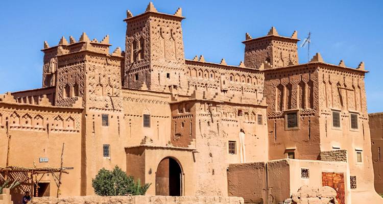 Earthen kasbah towers of Ait Benhaddou glowing under bright desert sunlight