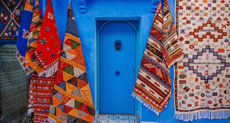 Colorful Moroccan carpets hanging beside a bright blue doorway