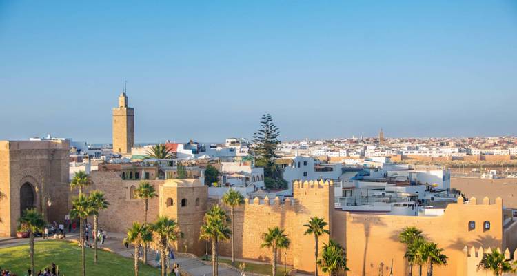 View over Rabat’s fortified walls, palm trees and Hassan Tower under a clear sky