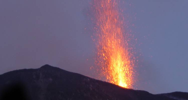 Fiery lava fountain erupting from Stromboli volcano against dusk sky