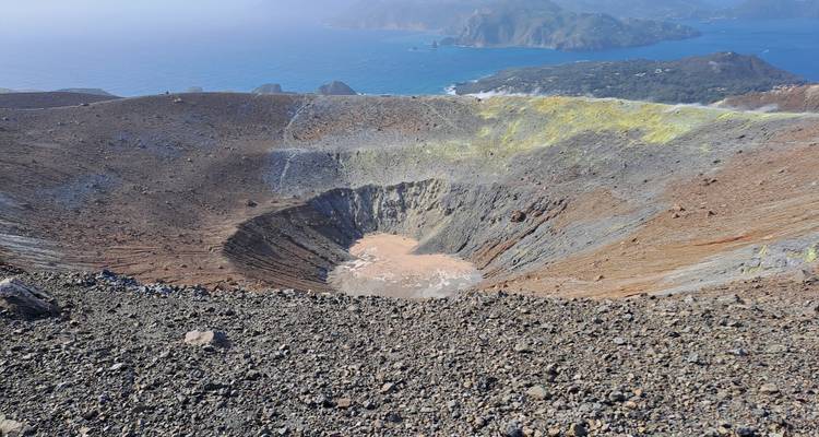 Smoky crater of an active volcano with yellow sulfur deposits overlooking the sea