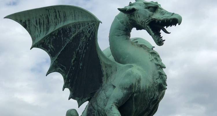 Close view of Ljubljana’s iconic green dragon statue against a cloudy sky.