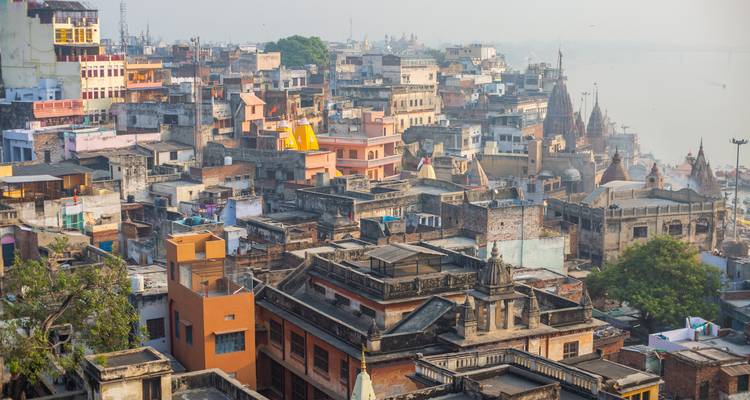 Los tejados de tonos pastel muy apretados de la ciudad vieja de Varanasi extendiéndose hacia el río Ganges brumoso
