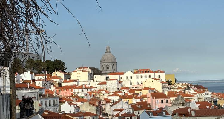 El clásico skyline del Alfama con sus tejados de tejas rojas y la cúpula gris del Panteón Nacional bajo cielos despejados.
